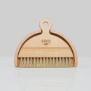 Brosse et pelle en bois de la marque Kavee sur fond gris clair