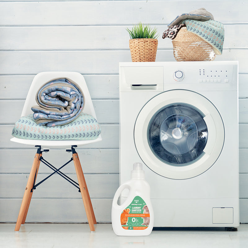 Désinfectant pour le linge de la marque Kavee dans une laverie au pied d'une machine à laver avec des sacs remplis de linge