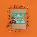 la boîte de plateau de fourrage bien-être pour cochons d'Inde et lapins de la marque Kavee entouré de pétales de fleurs bleues et jaunes sur fond orange